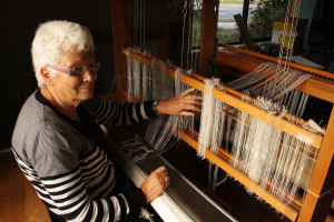 Kobi Brinkman demonstrates the begining of weaving at her loom.