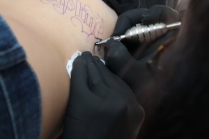 Skinks tattoo artist, Aimee, tattoos client on ribs. Photo: Karina Yanez